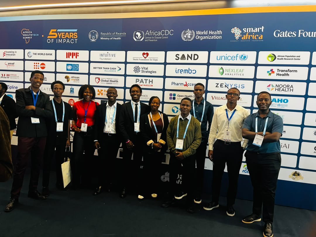 A large group of MedWell Club delegates in smart attire standing in front of the Africa HealthTech Summit sponsor wall.