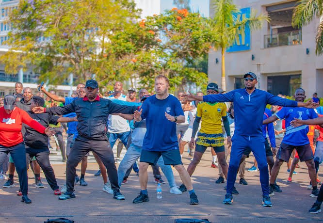 Participants in a mass stretching session at Kigali Car Free Day, led from the front by instructors.