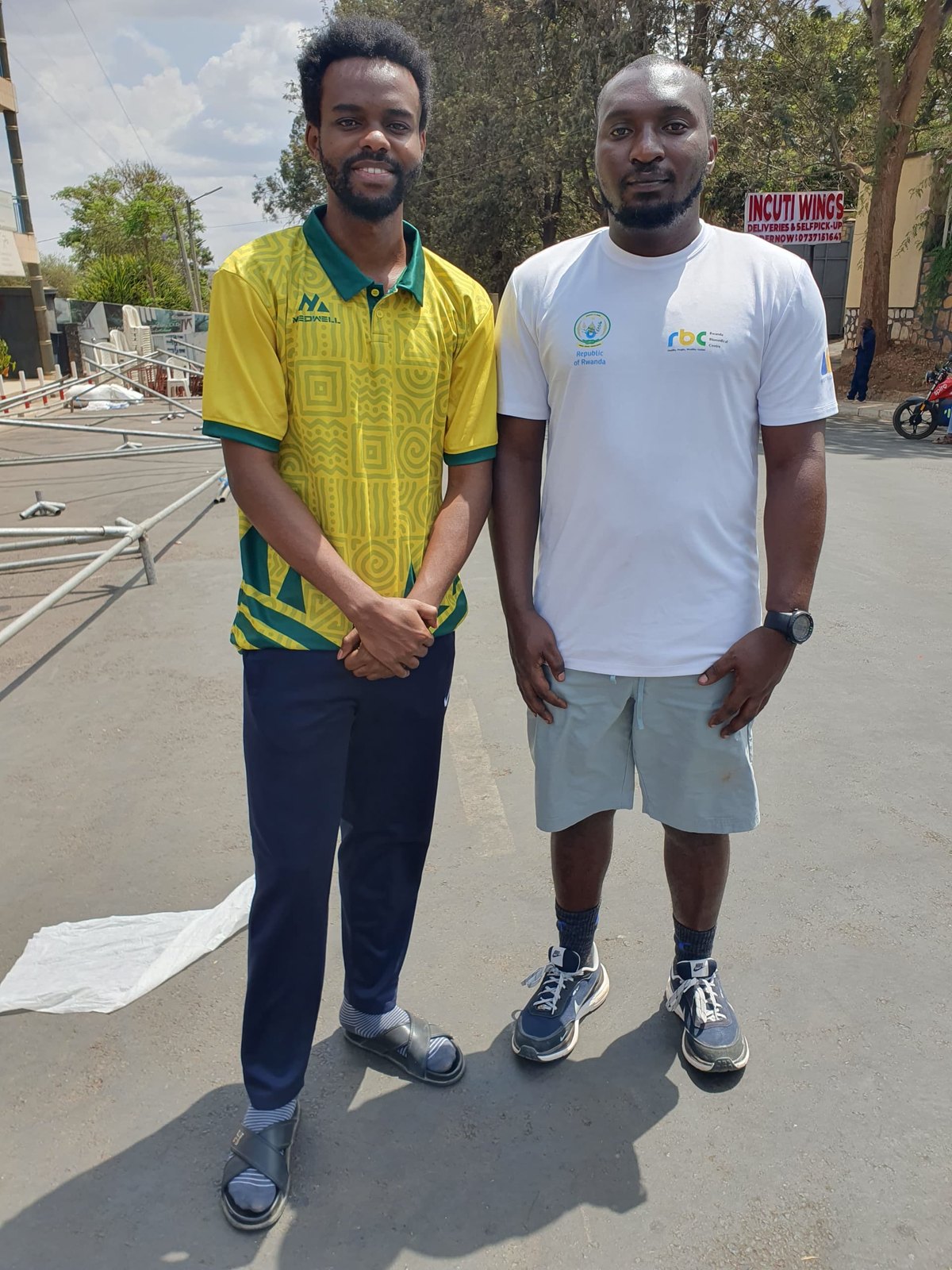 A MedWell Club member in a yellow jersey standing beside a representative of the Rwanda NCDs Alliance on the Car Free Day route.